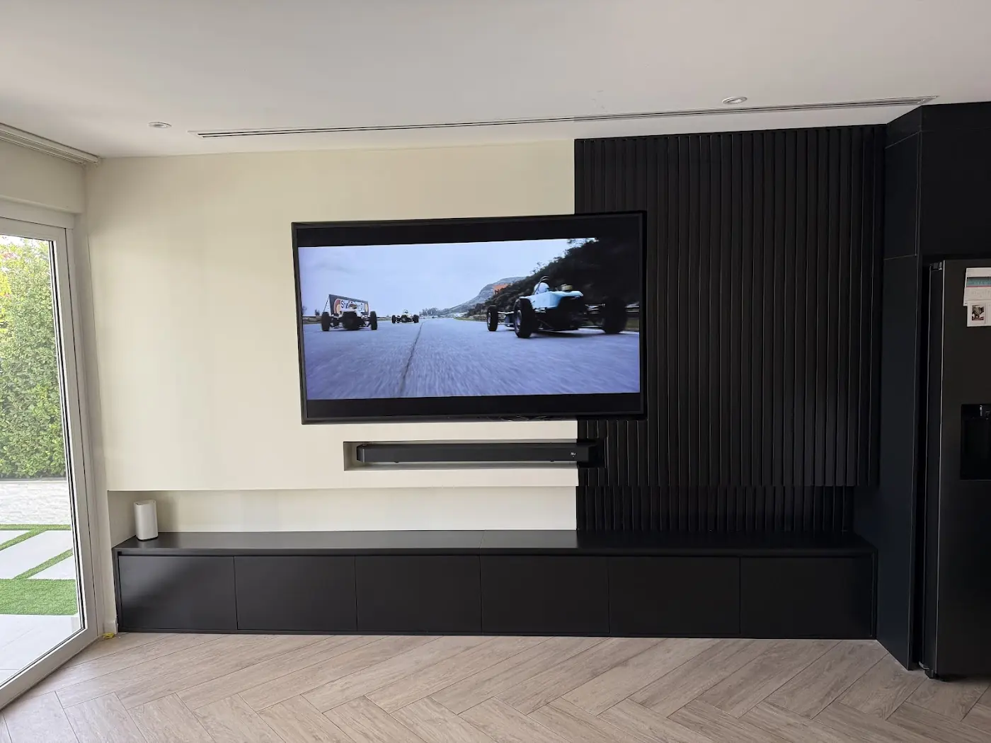 A media wall with black slatted panels and a floating TV unit, built and fitted by Bait AlNoor