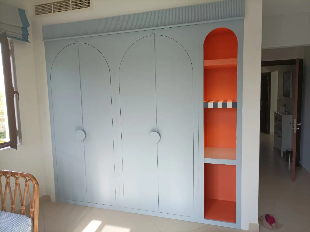 Built-in wardrobe with arched doors and a coloured open niche